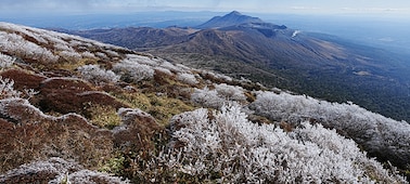 Un enorme paisaje que muestra una serie de montañas. El enfoque está en la montaña en el fondo cubierta de nieve